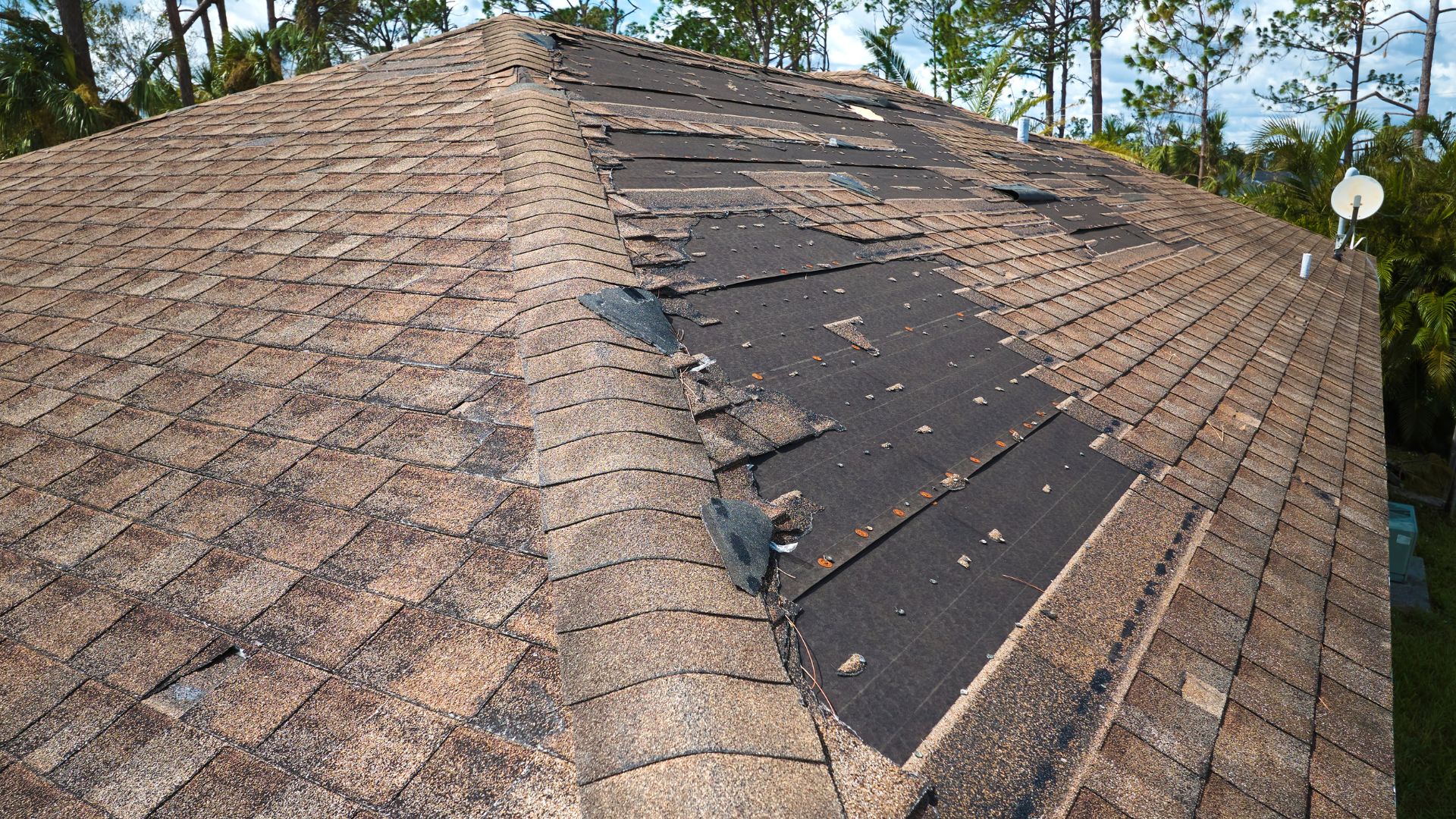 A roof with a broken shingles and a broken window