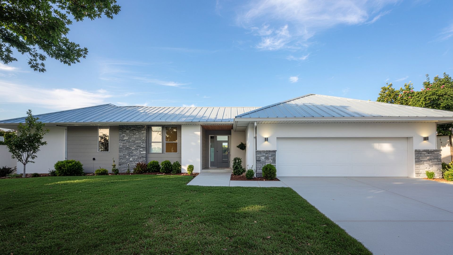 Modern single-story house with stone accents, white exterior, and attached garage