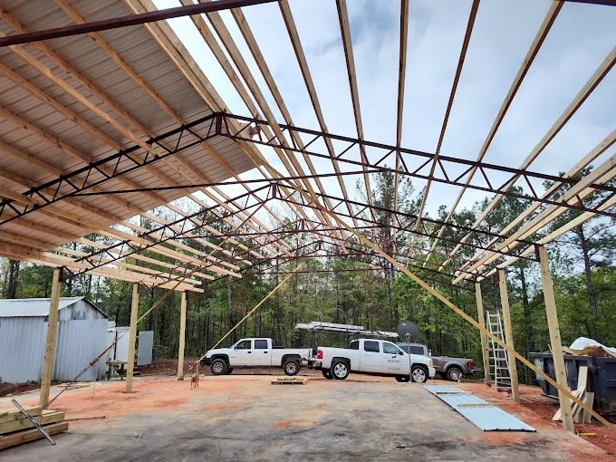 Wooden frame structure under construction with white trucks parked inside