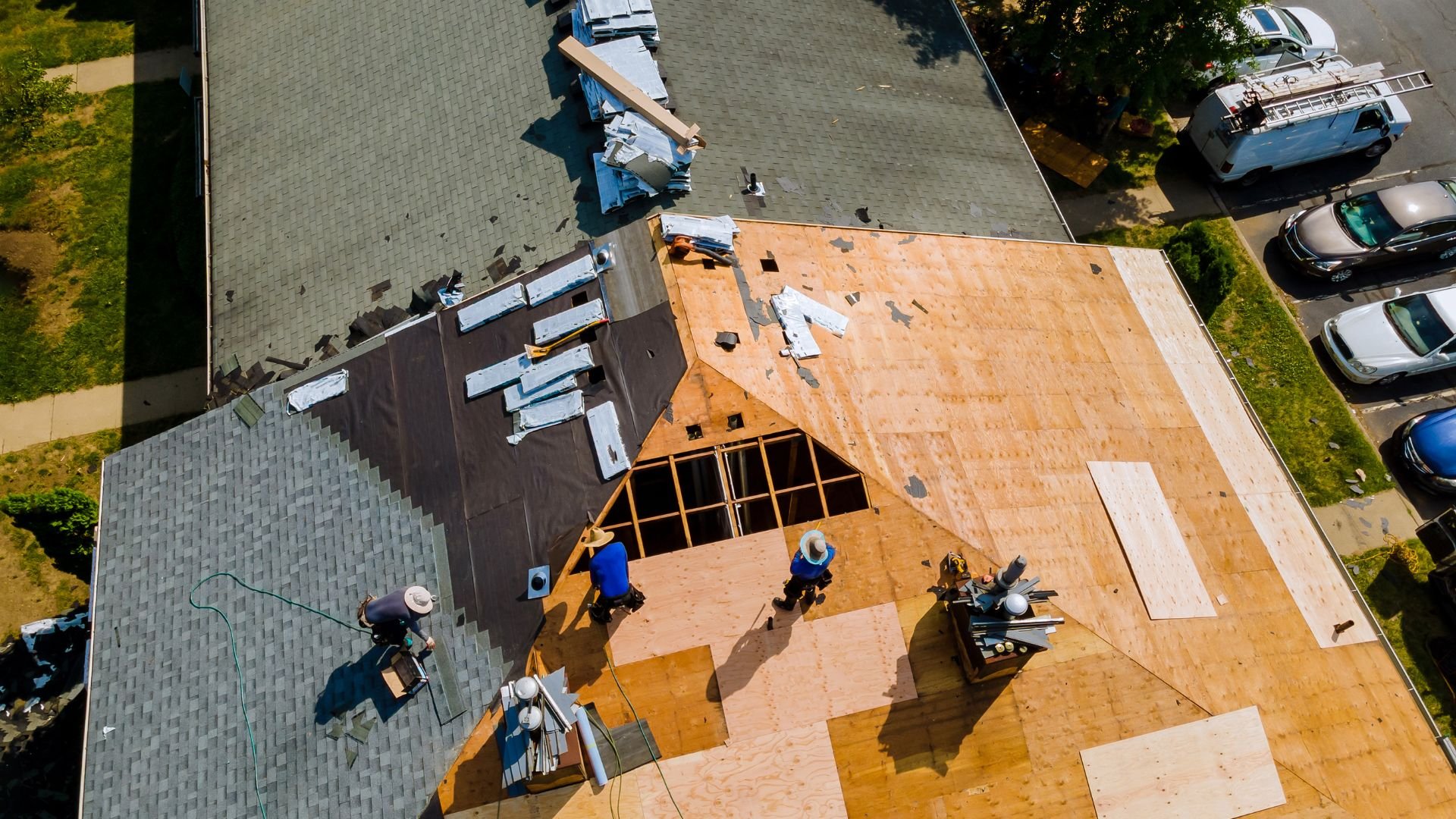 Aerial view of roofers working on multiple roofs with construction materials